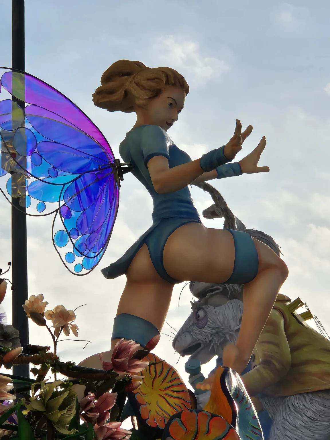 Une fée en papier mâché aux ailes de papillon violettes et bleu clair, sur un char du Carnaval de Viareggio