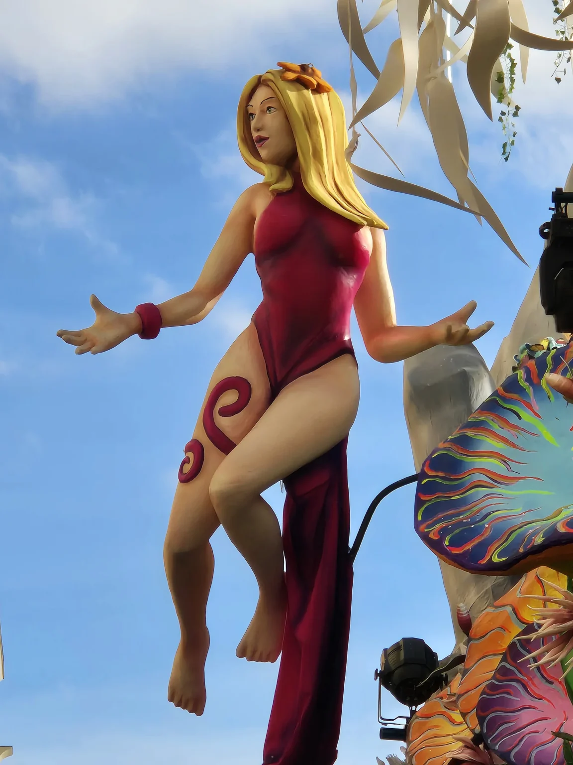 Un personnage en papier mâché aux cheveux blonds, suspendu au-dessus d'un char du Carnaval de Viareggio