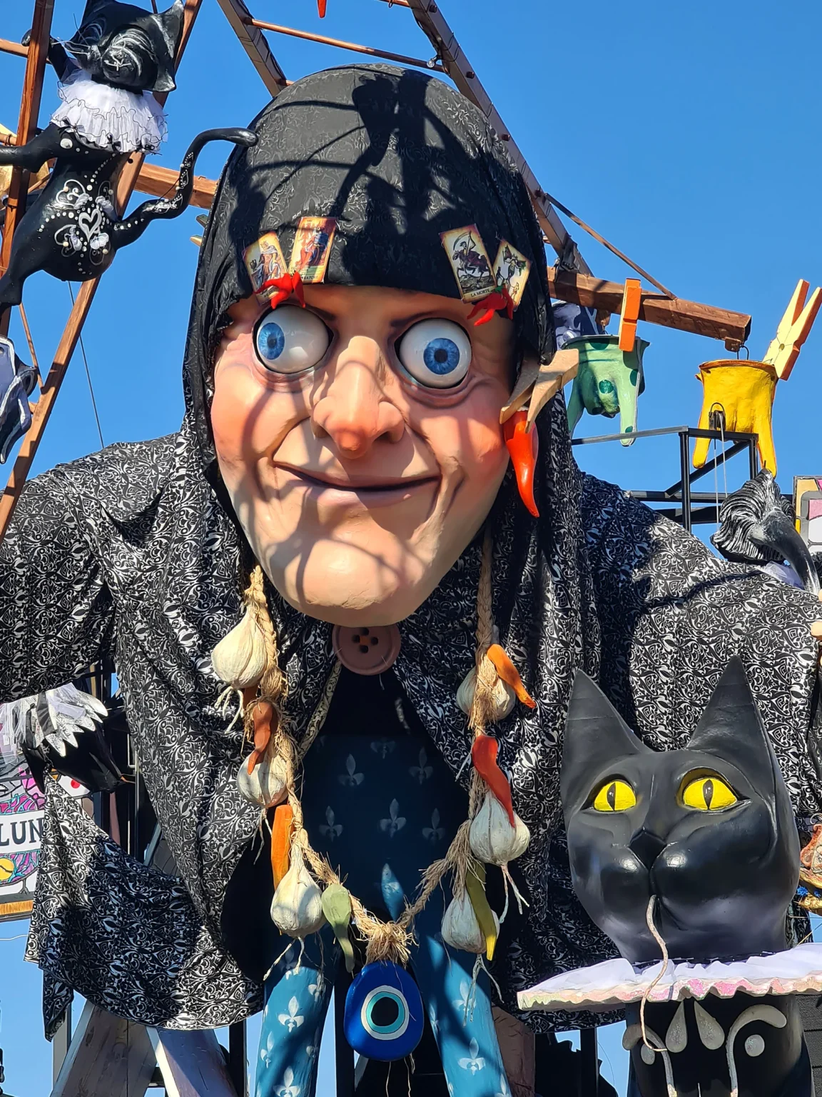 Une sorcière en papier mâché avec des lunettes, des amulettes et un chat noir, sur un char du Carnaval de Viareggio