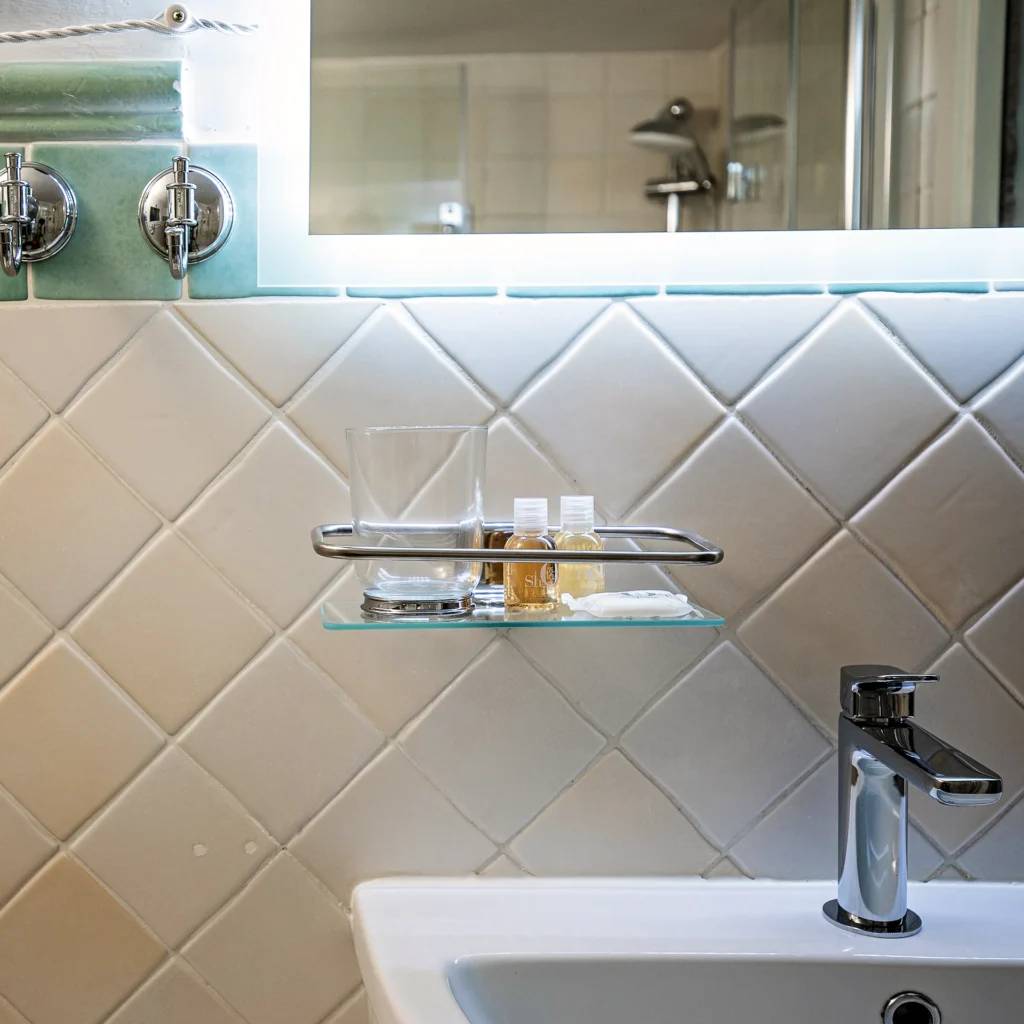El lavabo y la repisa de cristal del baño de la Habitación Dorada