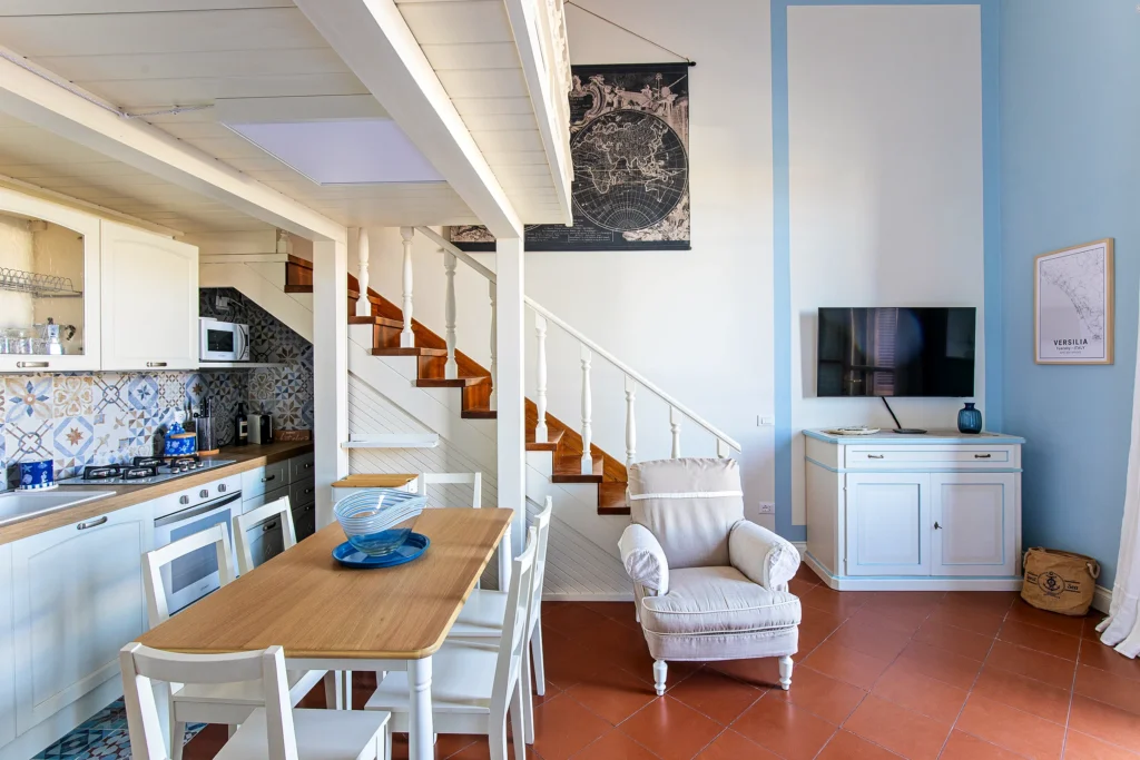 La zona de día vista desde la cocina: la mesa, el sillón y la escalera del altillo