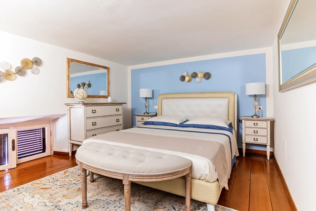 La Habitación Dorada en el altillo, con la cama de matrimonio, el banco tapizado y la alfombra