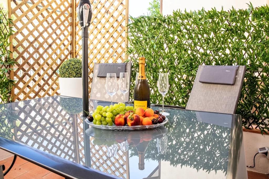 Fruta fresca, copas y una botella sobre la mesa del patio