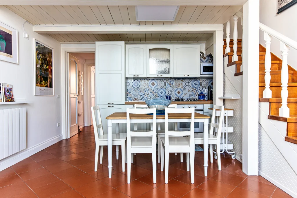El comedor con la mesa para seis, la cocina y la escalera de madera que sube al altillo