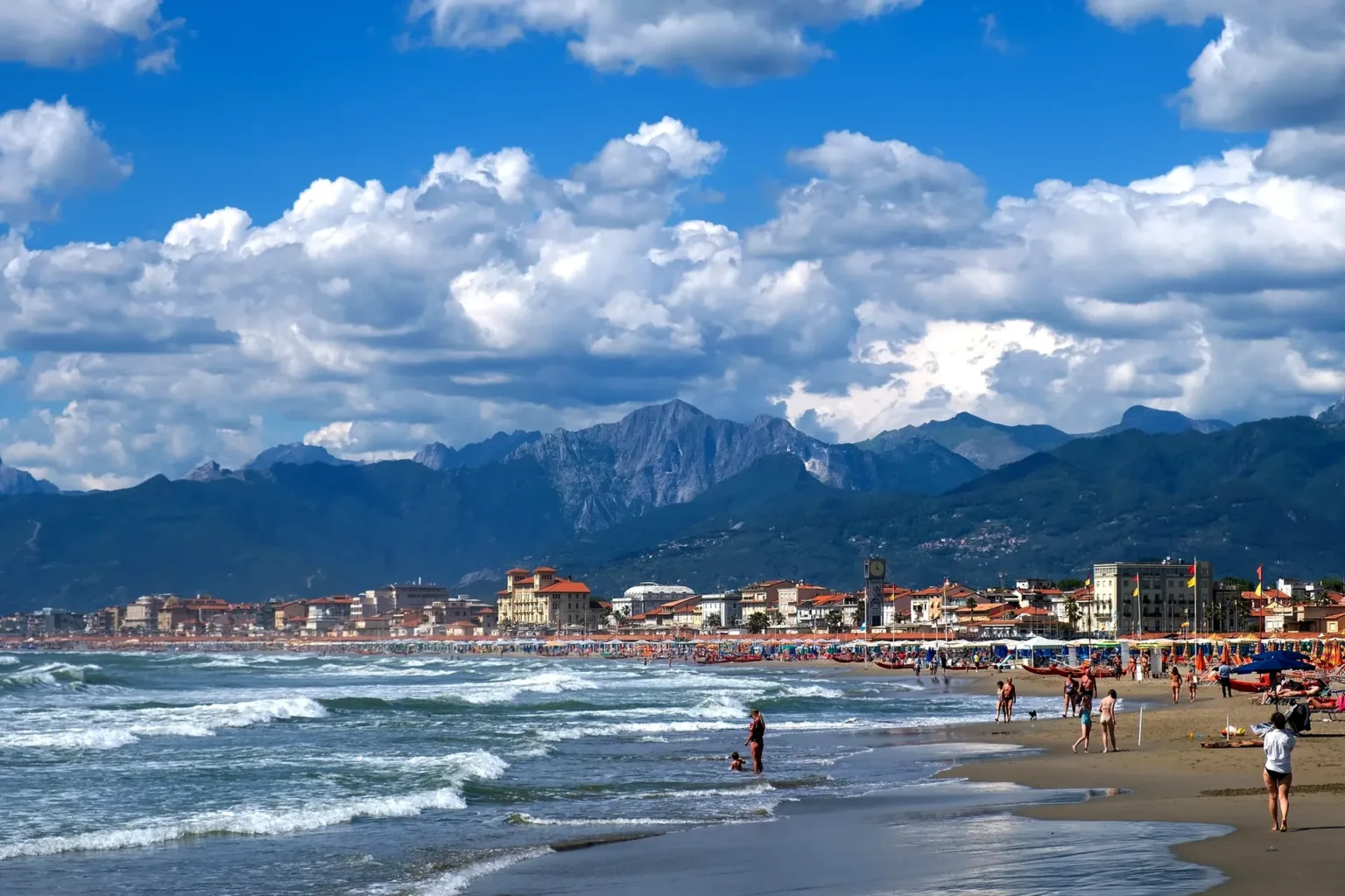 La spiaggia di Viareggio con le onde e le Alpi Apuane dietro la città
