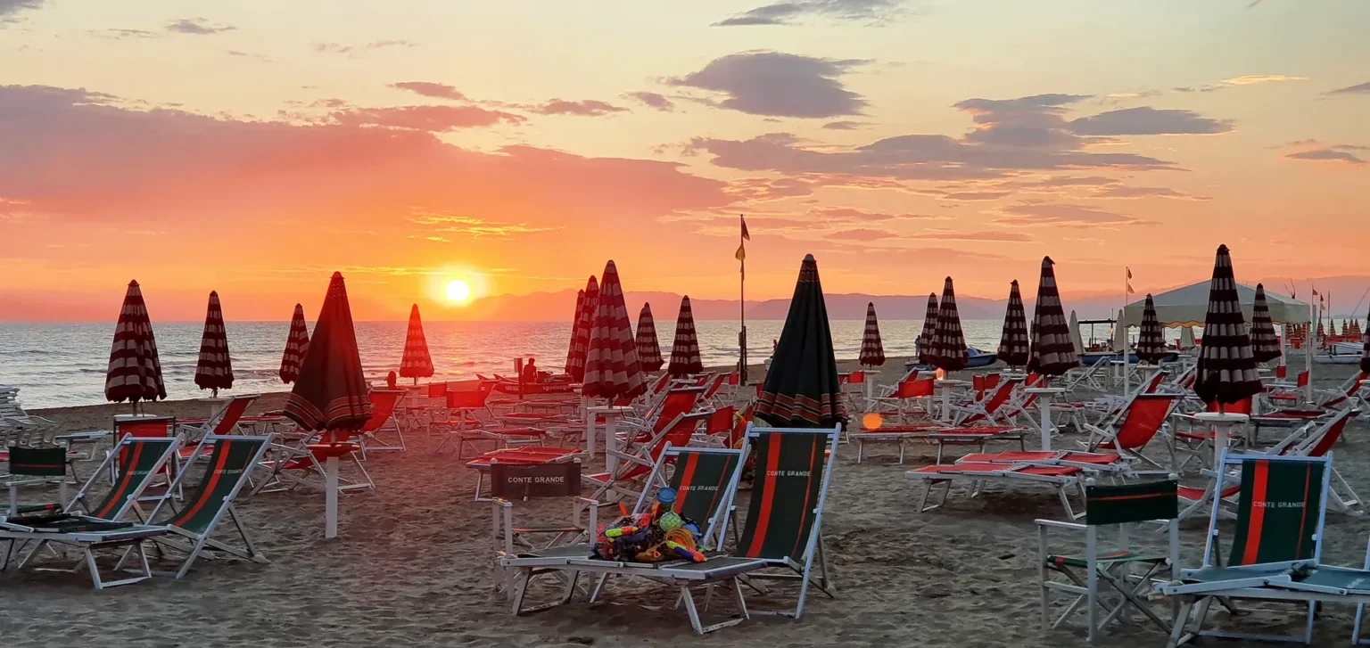Il tramonto tra gli ombrelloni chiusi sulla spiaggia di Viareggio, a luglio