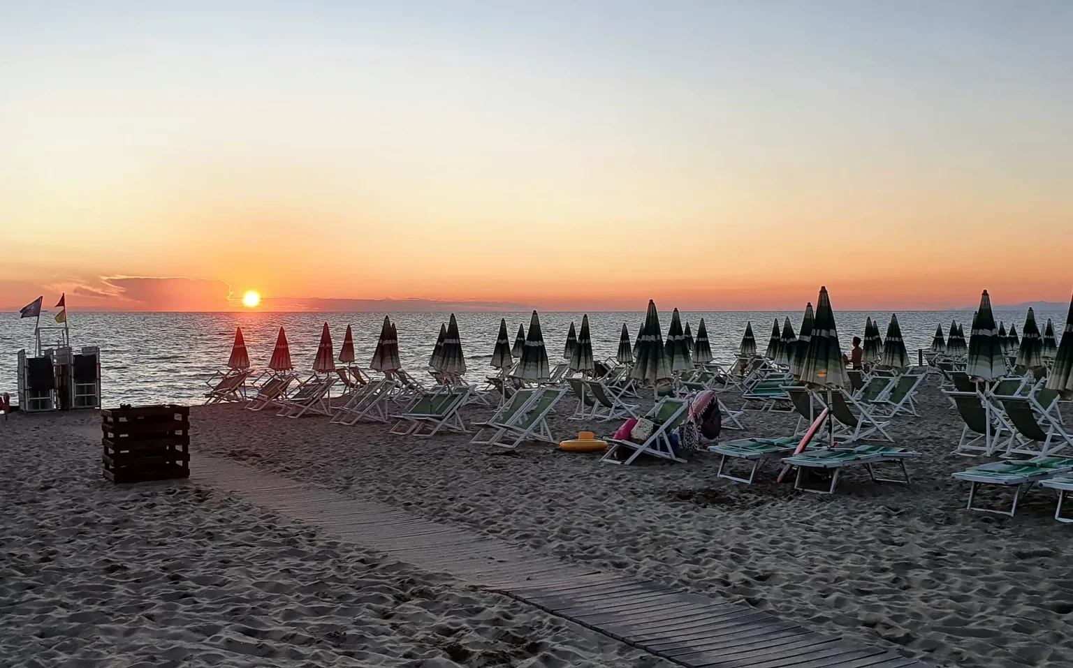 Il tramonto sul mare di Viareggio, in fondo alla passerella tra gli ombrelloni
