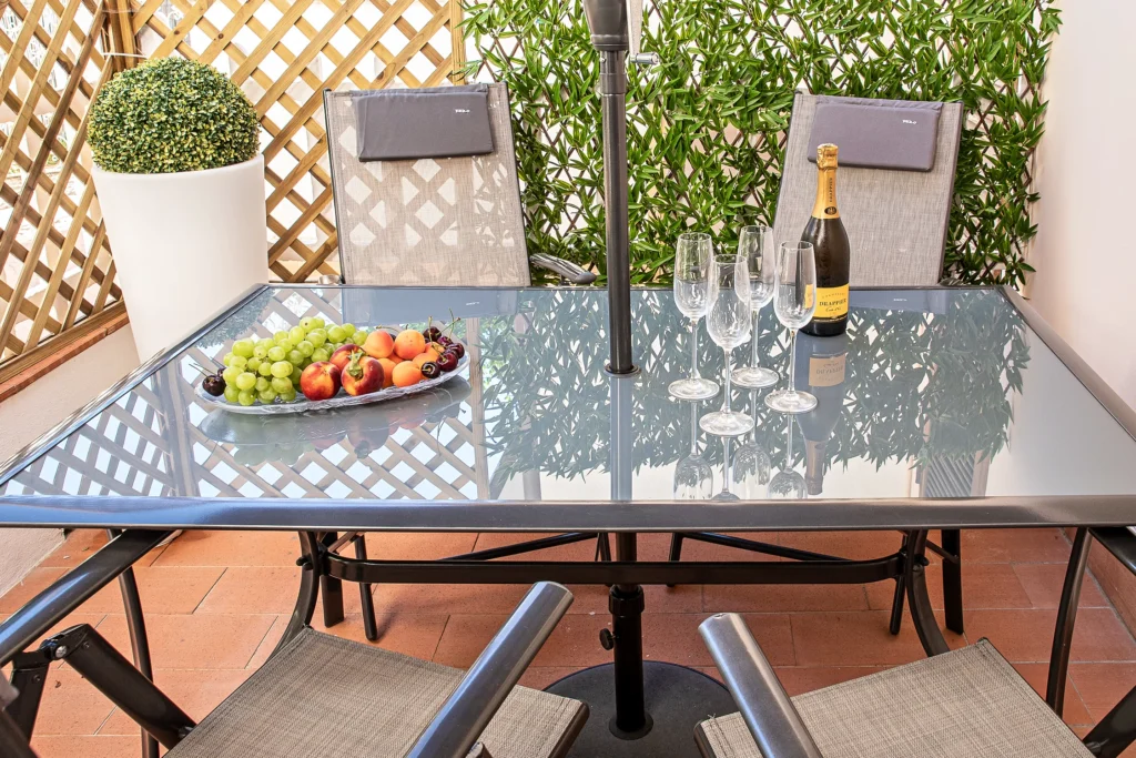 Il tavolo del patio privato apparecchiato per l'aperitivo, con frutta, calici e una bottiglia