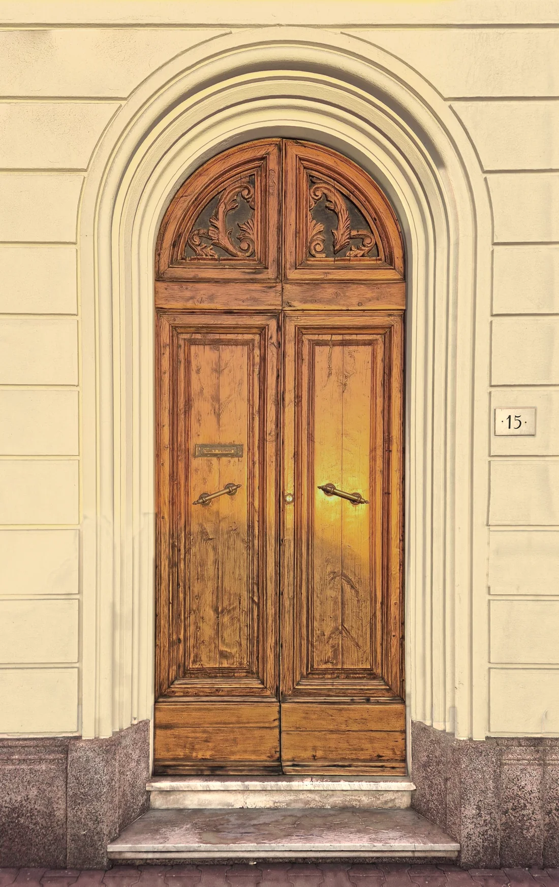 Il portone in legno del palazzo di Viale Carducci 15 a Viareggio, illuminato dal sole, con la targa del numero civico